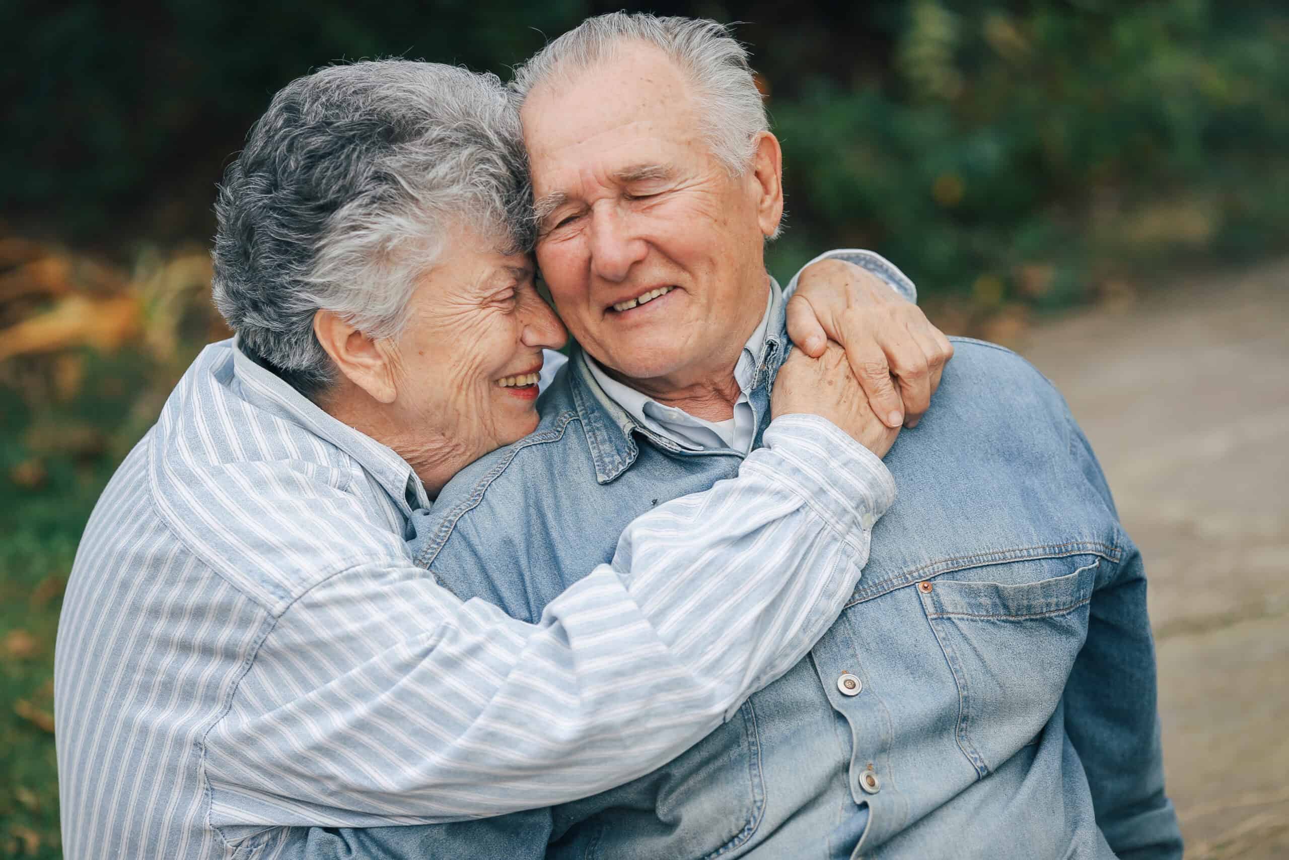 An image of two older people sitting in a park one providing carer support for mental health challenges