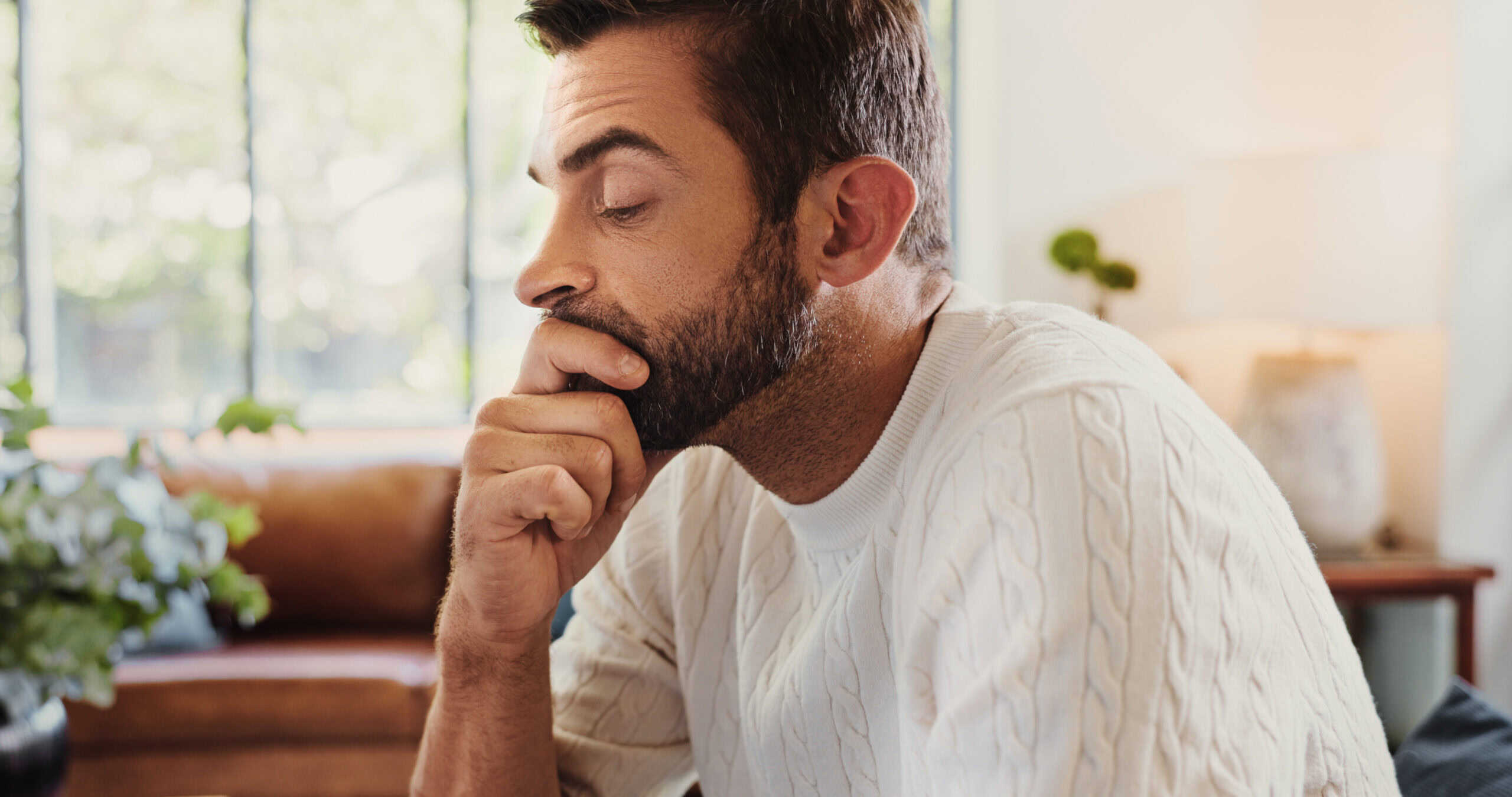 A man sitting inside, looking nervous, and tense, experiencing symptoms of generalised anxiety disorder (GAD).